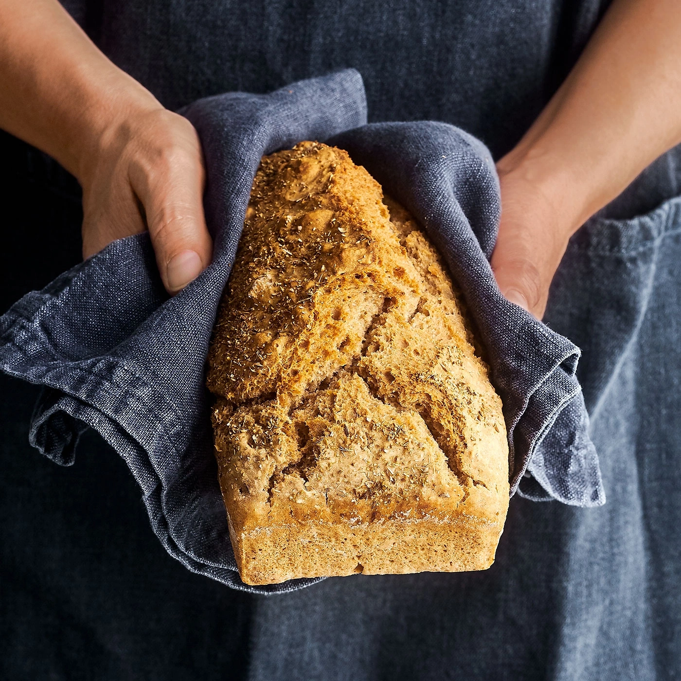 Gros plan d'une personne tenant du pain dans un tissu bleu, rustique, nourriture, boulangerie