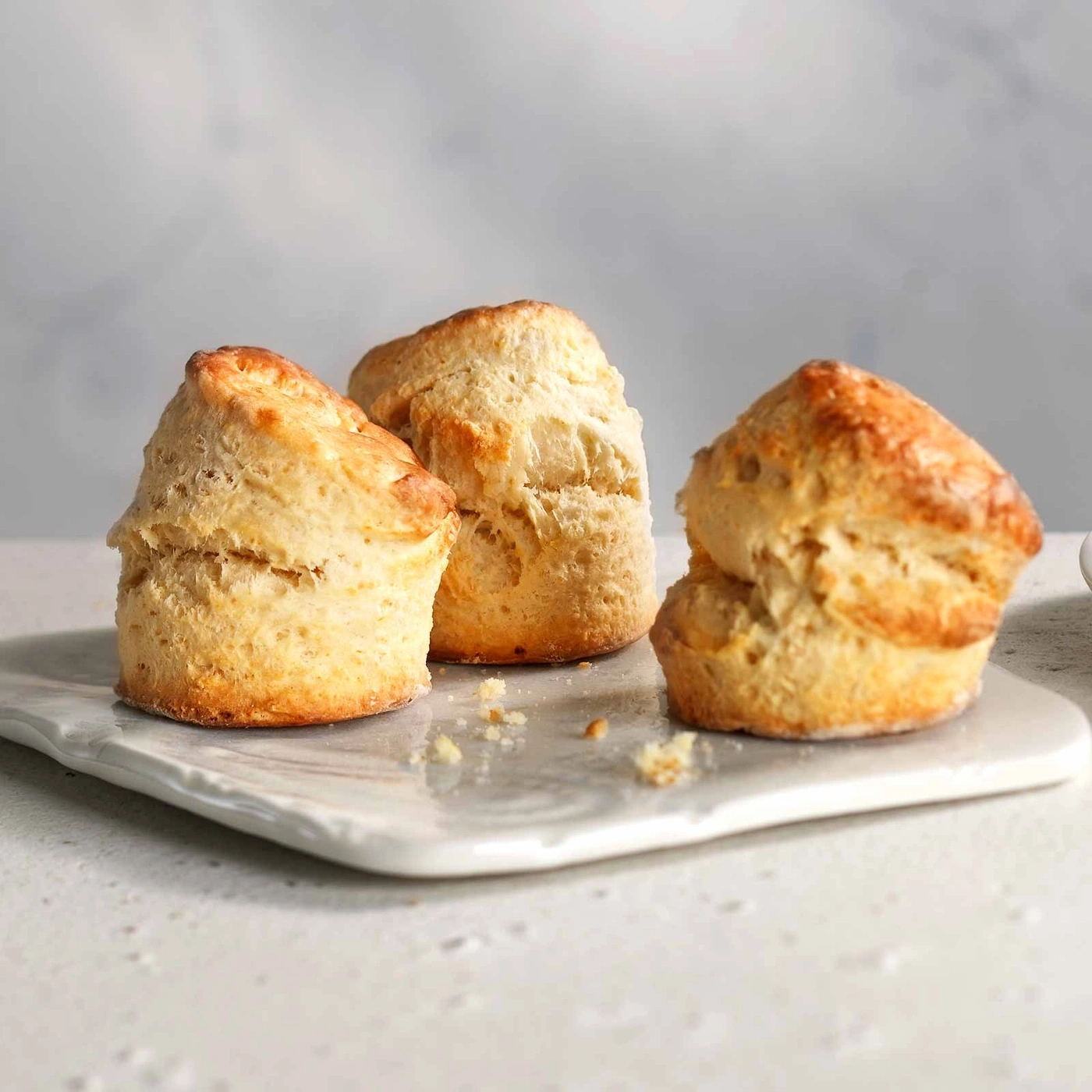 Drei goldbraune Scones auf einem weißen Teller, Nahaufnahme, lecker