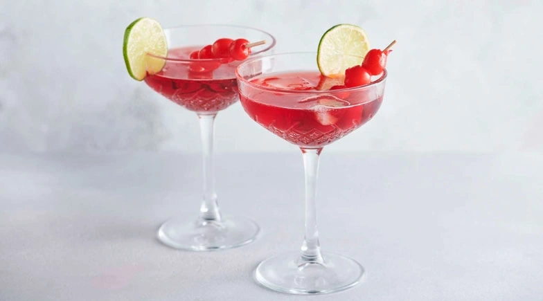 Zwei Cocktails mit Limetten und Kirschen auf weißem Hintergrund