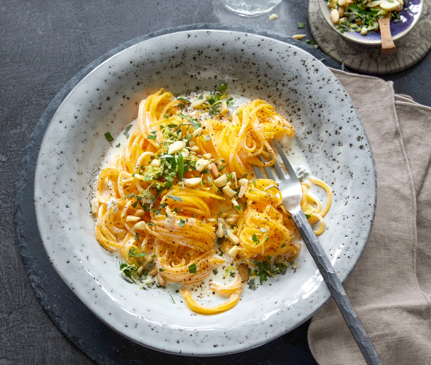 Pasta mit Sahnesauce, Kräutern und Pinienkernen auf einem Teller