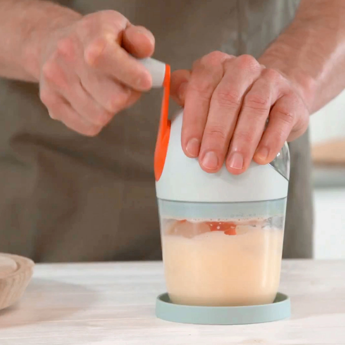Gros plan d'une personne utilisant un mixeur pour traiter un liquide.