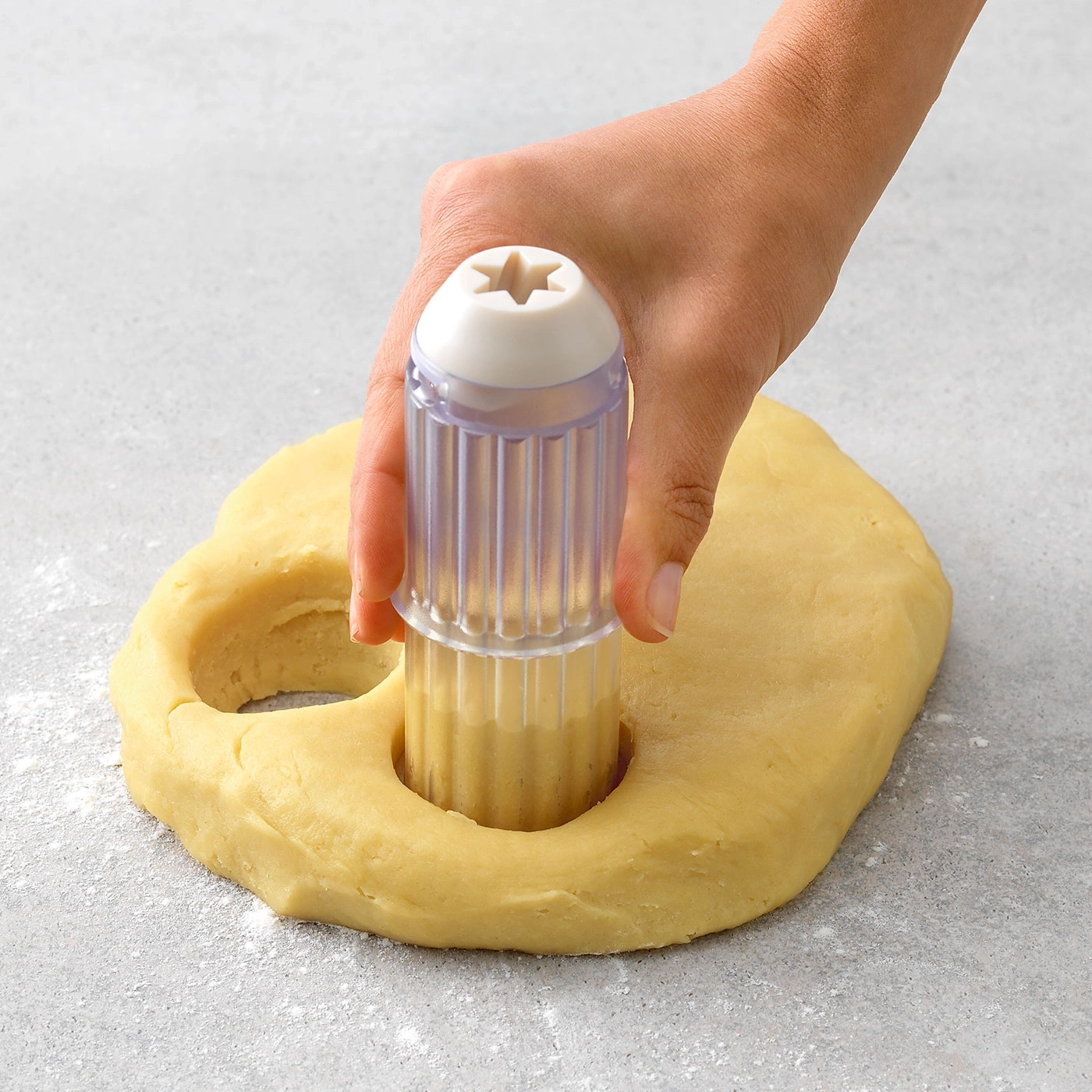 Hand drückt Ausstecher in Teig, um Kekse zu formen. Backen, Küche, Kochen.