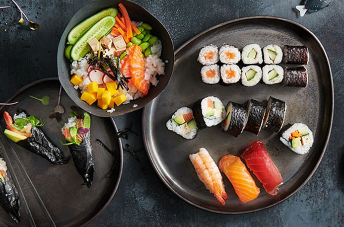 Sushi-Gerichte auf einem dunklen Teller, köstlich und appetitlich angerichtet.