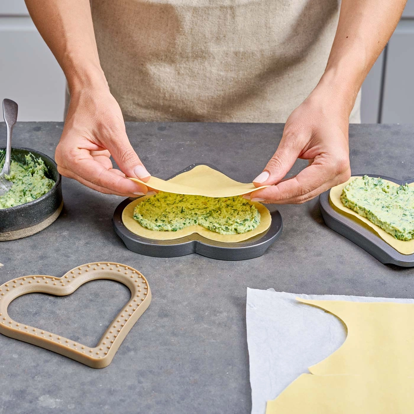 Personne préparant des raviolis en forme de cœur, avec de la pâte et de la farce.