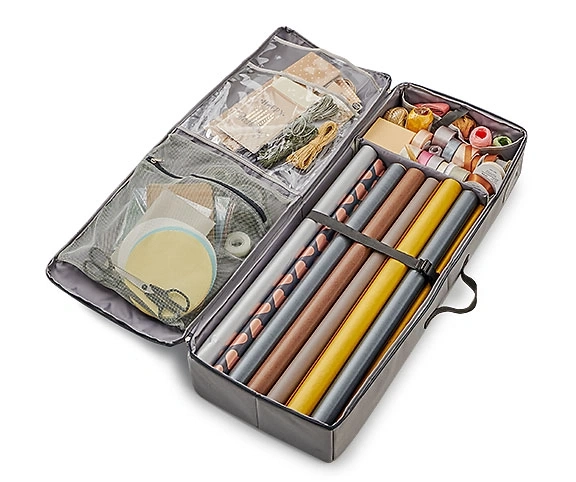 Organisateur de papier cadeau avec papier cadeau, rubans et accessoires, ouvert, sur fond blanc.
