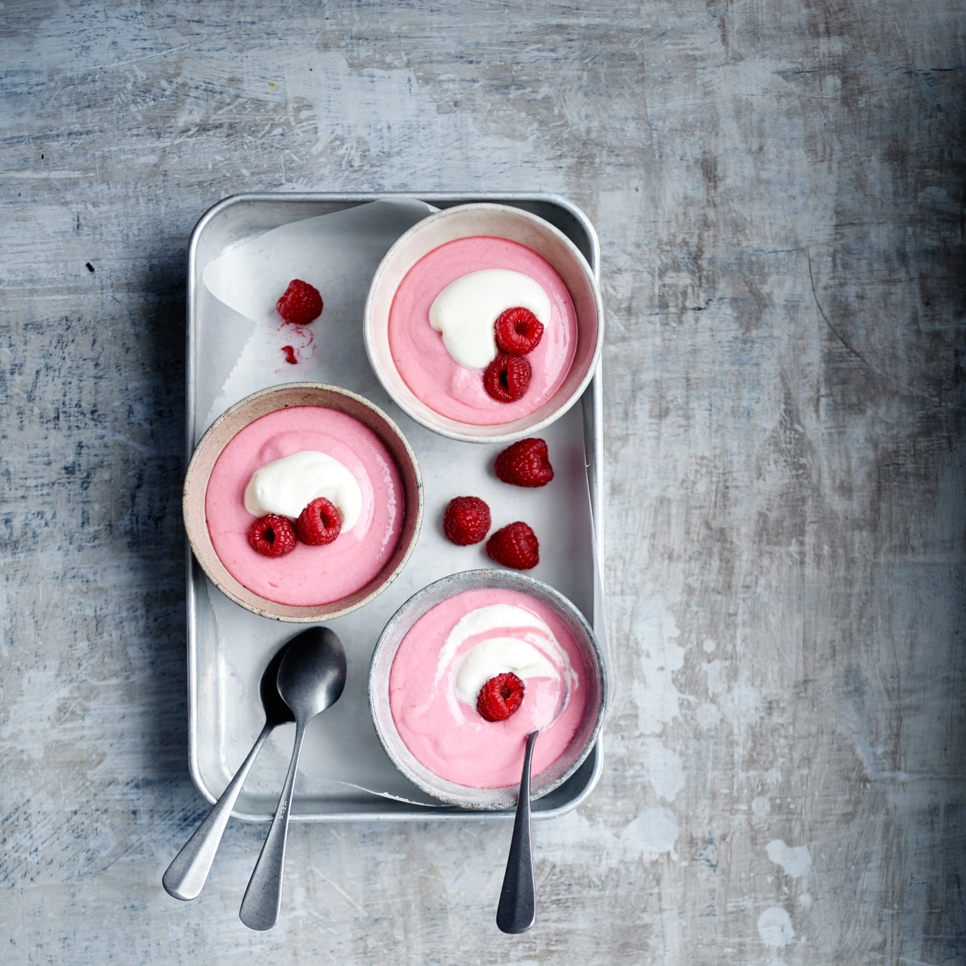 Purée de framboises avec crème et framboises fraîches dans des bols sur plateau
