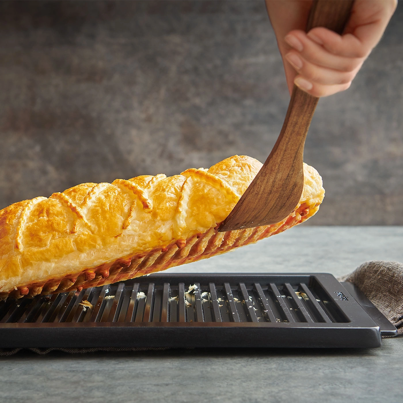 Une pâtisserie savoureuse est soulevée d'un grill avec une spatule en bois.