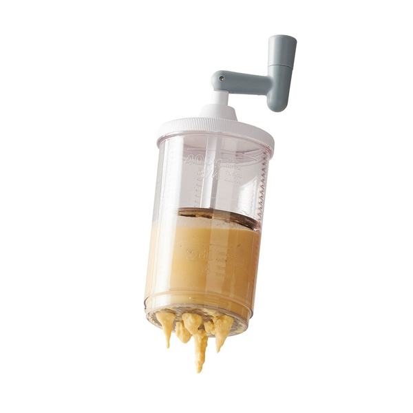 Distributeur de pâte avec ouvertures, rempli de pâte, isolé sur fond blanc