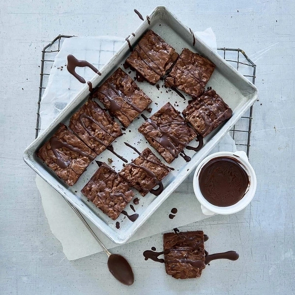 Schokoladenbrownies auf einem Tablett mit Schokoladensauce und Löffel