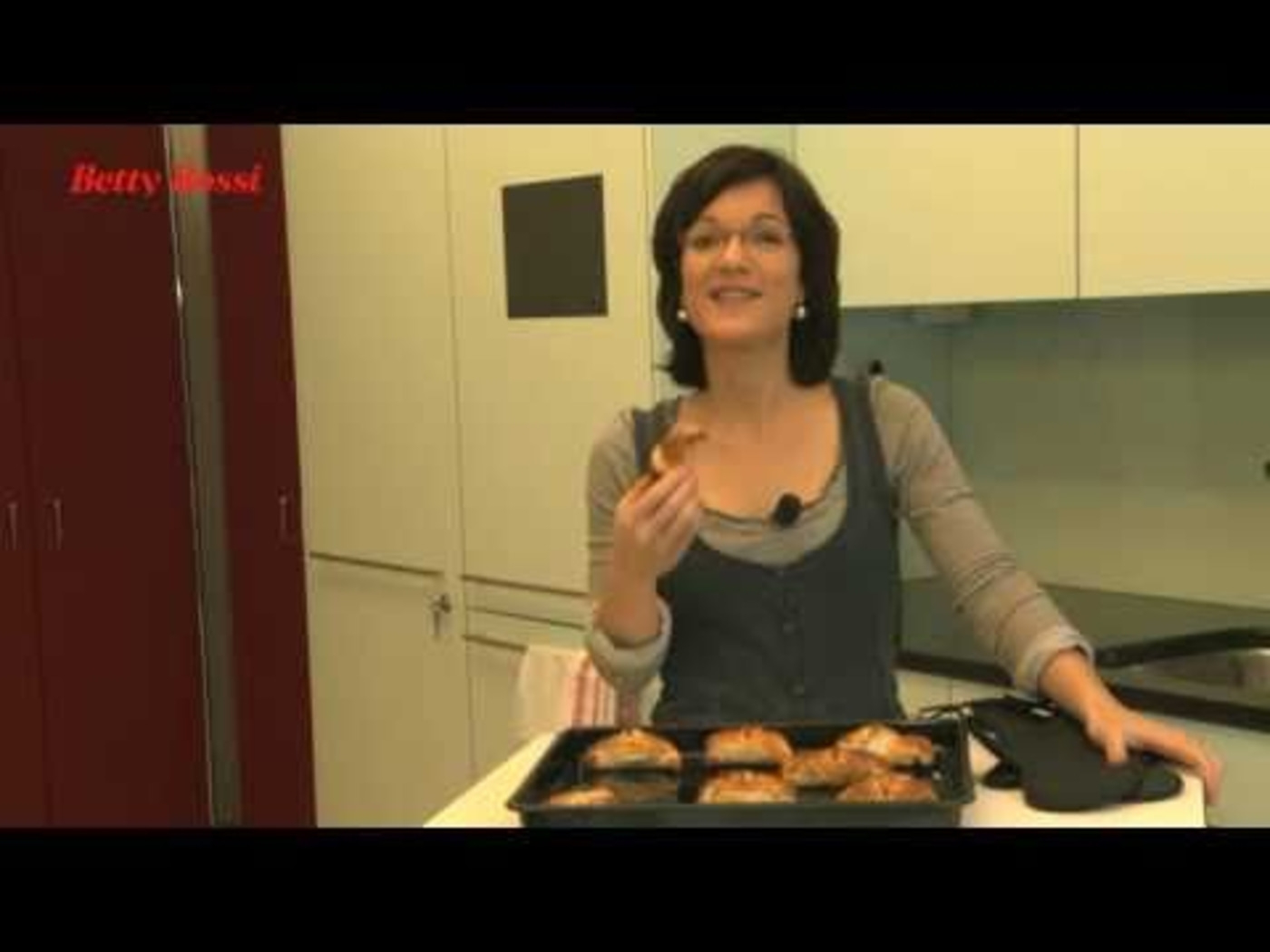 Femme tient pâtisserie dans cuisine, plaque de cuisson avec pâtisseries, logo Betty Bossi