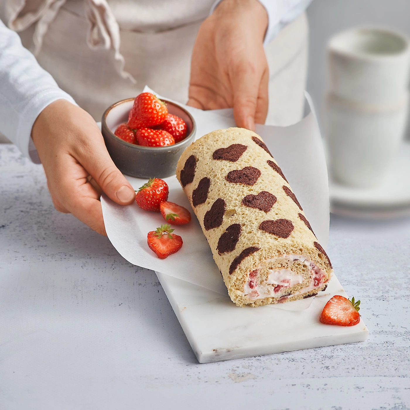 Bûche roulée aux fraises et taches de chocolat, accompagnée de fraises.