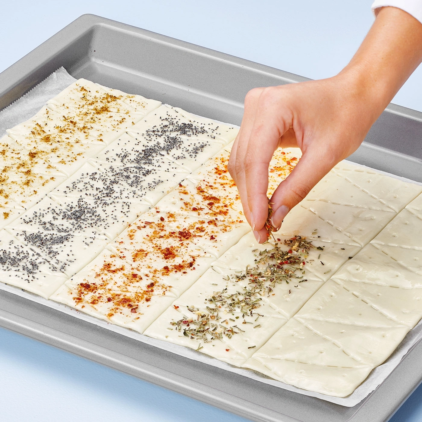 Hand bestreut Gebäck mit Kräutern, Backblech, verschiedene Gewürze, Nahaufnahme