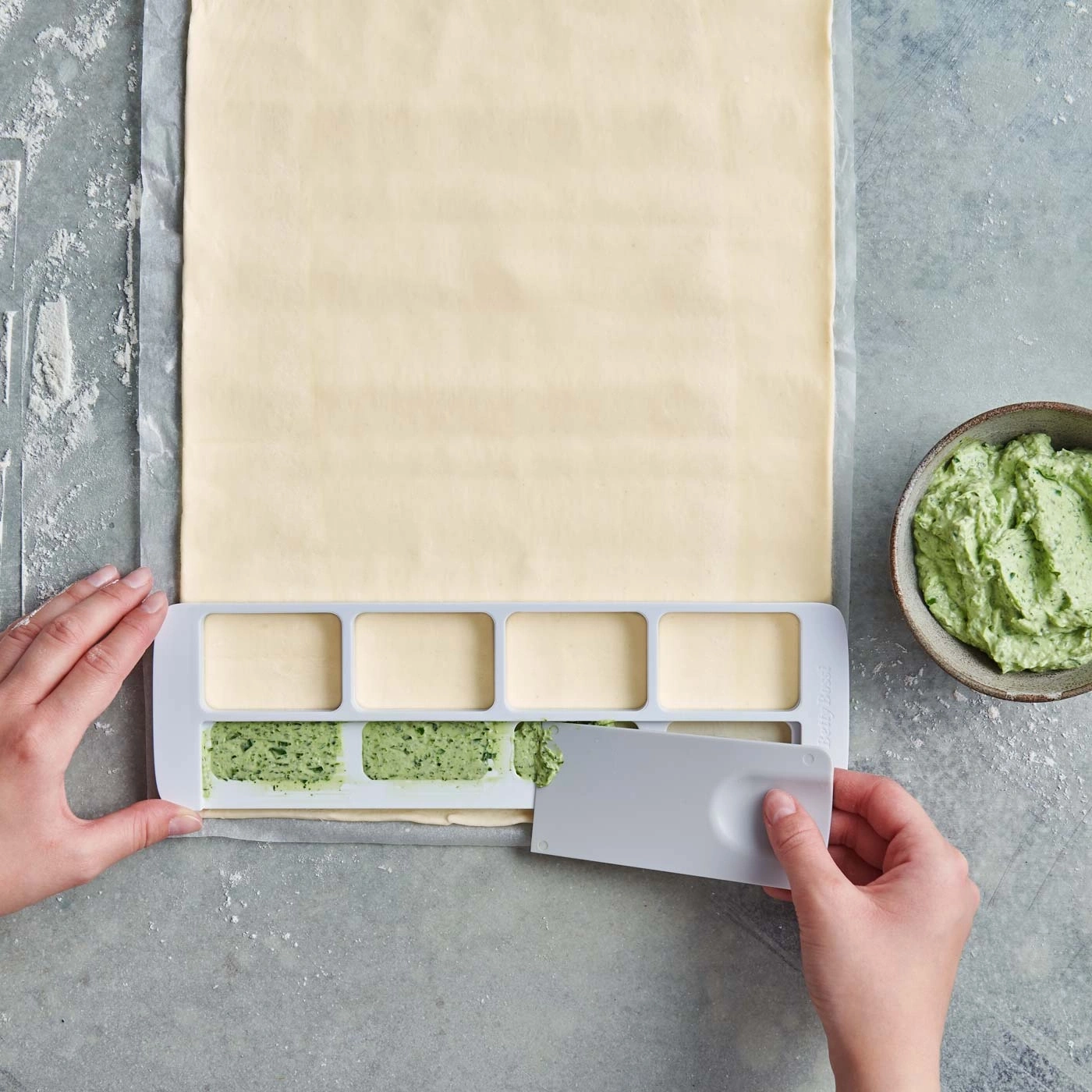 Blätterteig mit Kräuterbutter, Werkzeug, Hände, grauer Hintergrund, Nahaufnahme
