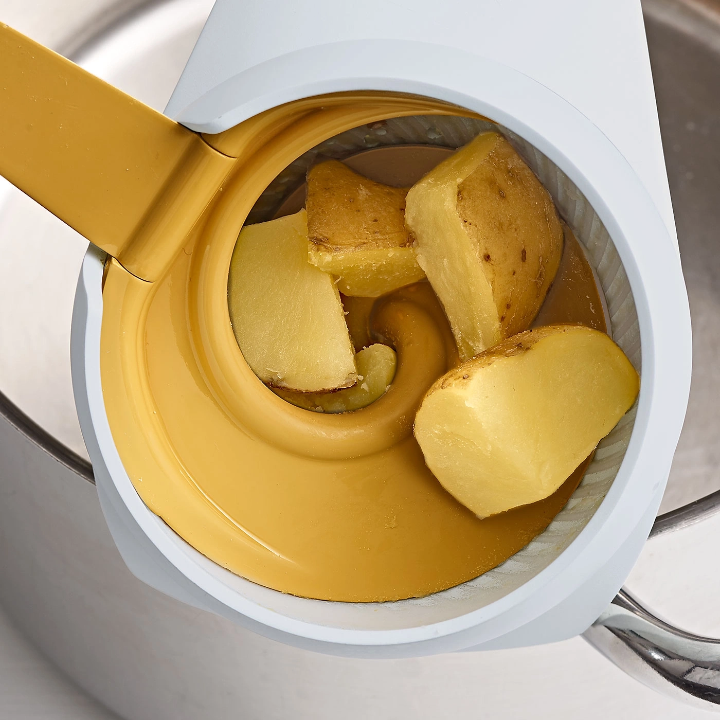 Pommes de terre dans un appareil de cuisine, jaune et blanc, gros plan, préparation culinaire