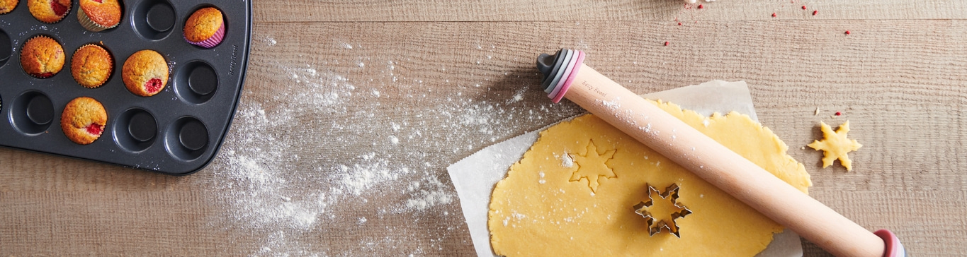 Backen mit Teig, Ausstechern und Muffins auf Holzuntergrund