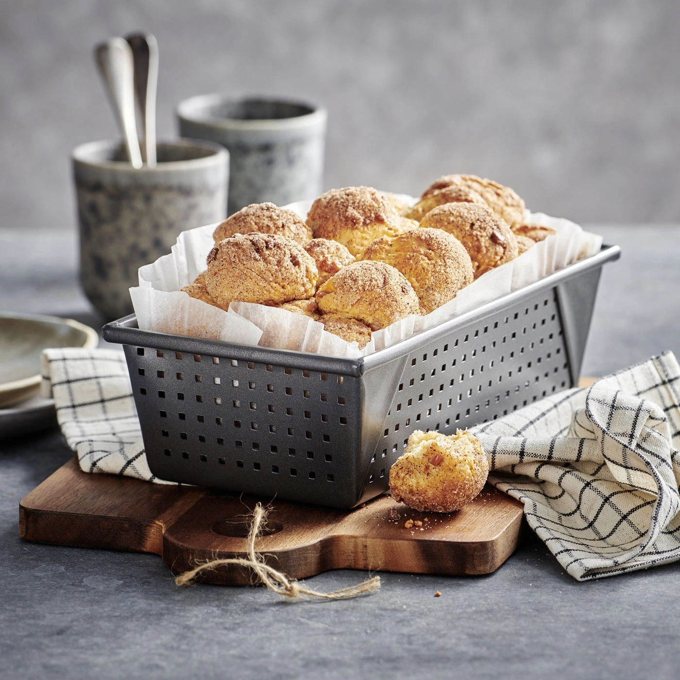 Délicieux petits pains dans un panier sur une planche de bois avec une serviette en tissu.