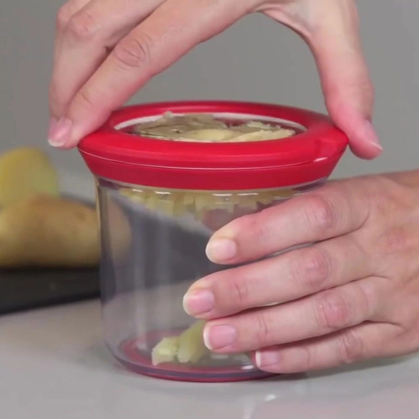 Hände schließen roten Deckel auf einem Glas mit Kartoffeln. Nahaufnahme.