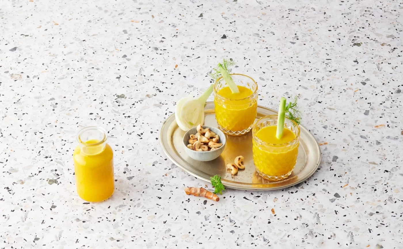 Boisson jaune avec fenouil et noix de cajou sur plateau.