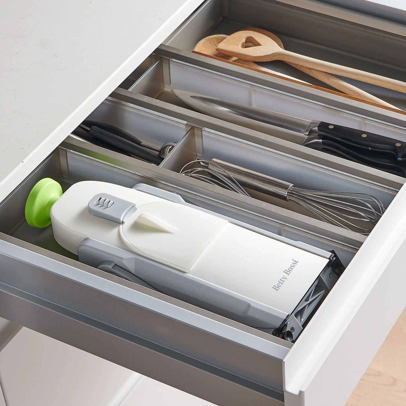 Küchenschublade mit Küchenutensilien, darunter ein Gemüseschneider und Kochlöffel.