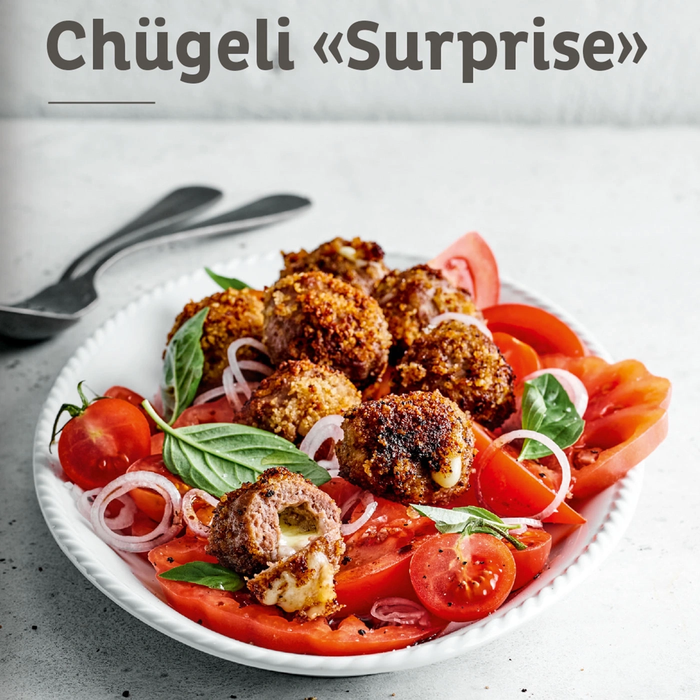 Chügeli «Surprise» auf einem Teller mit Tomaten und Zwiebeln, lecker.