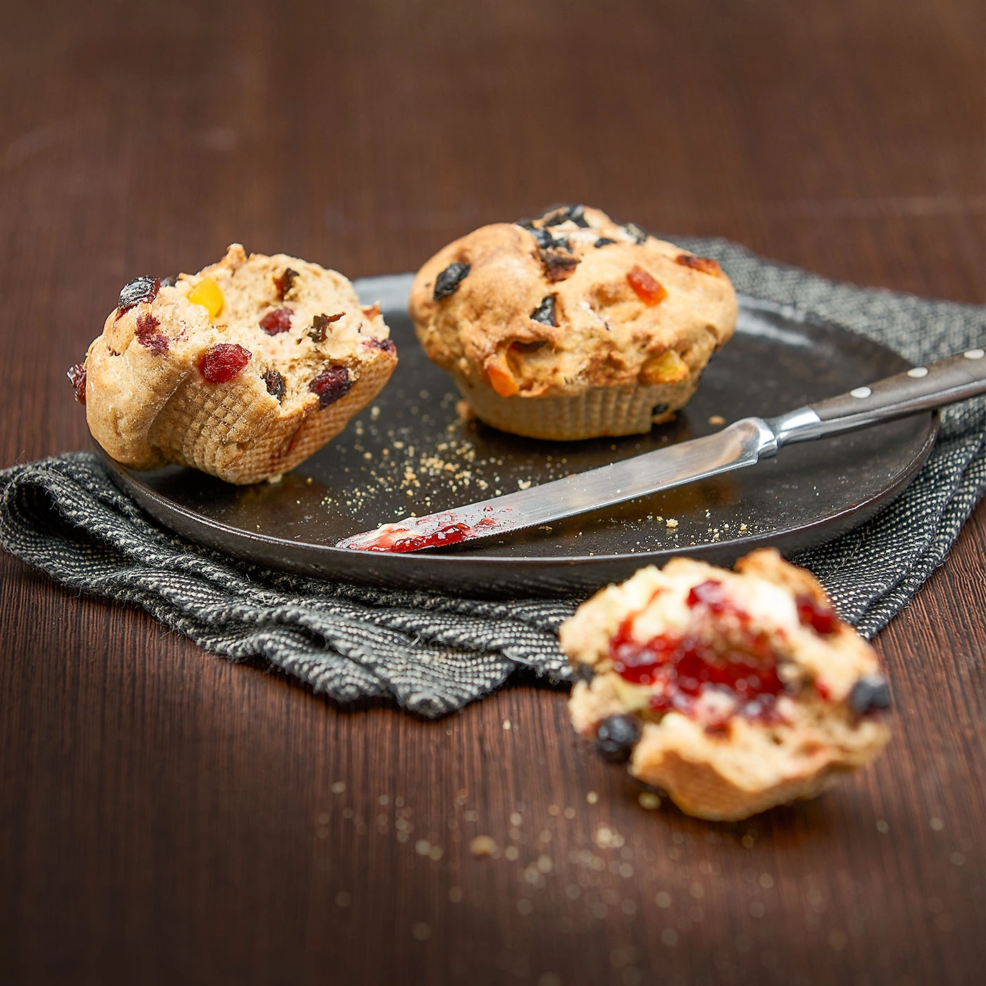 Muffins mit Früchten auf einem Teller mit Messer und Marmelade
