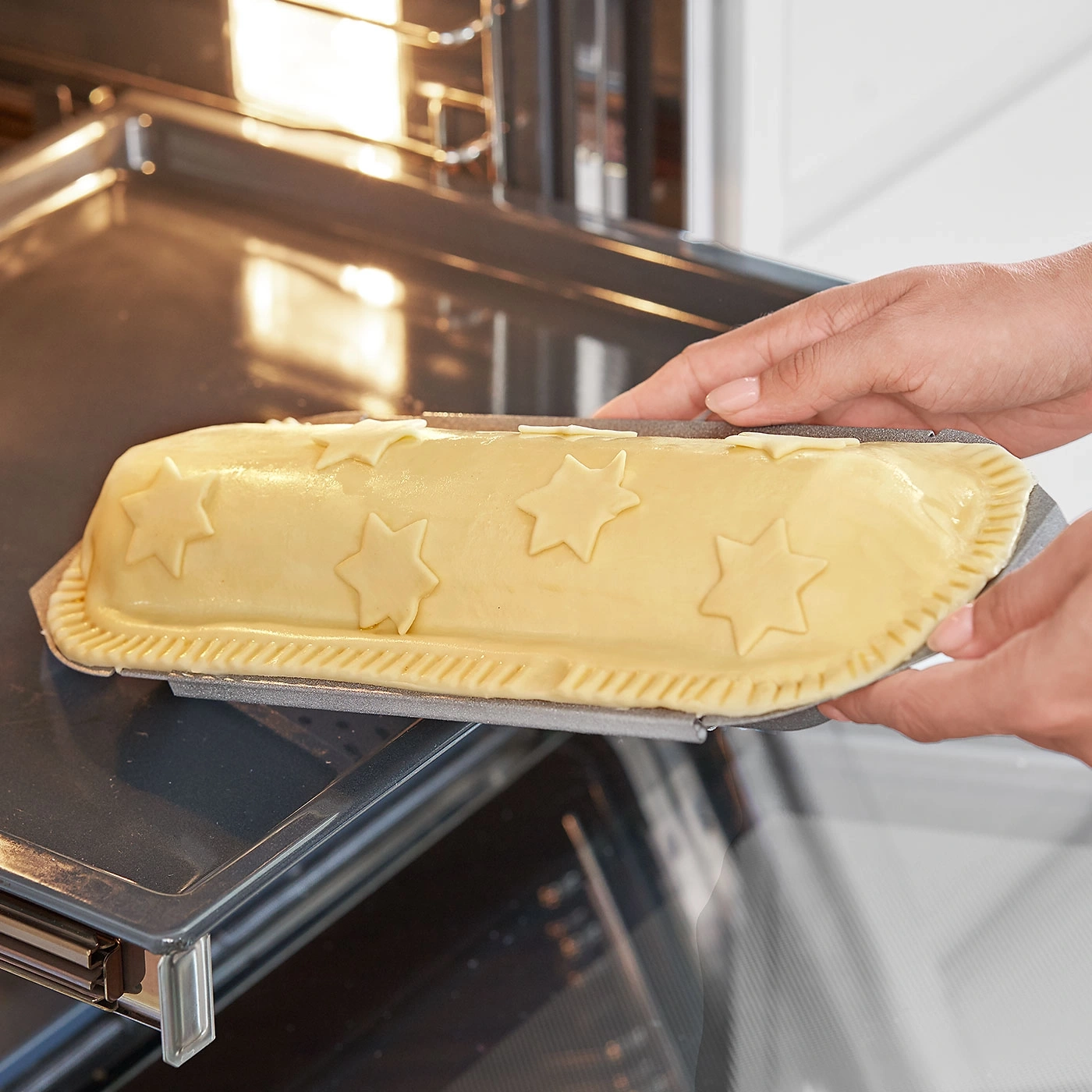 Ein Kuchen mit Sternen wird in den Ofen geschoben, Backen, Küche, Essen.