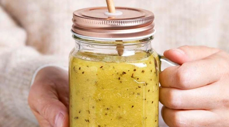 Ein Glas Smoothie mit Deckel und Strohhalm, gehalten von einer Person.