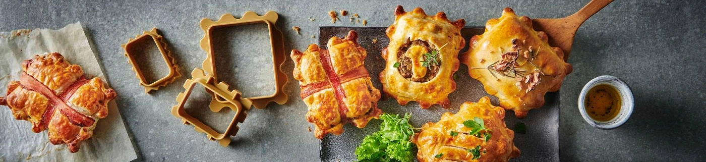 Gebäck mit Speck, Rahmen, Kräutern und Soße auf grauem Hintergrund.