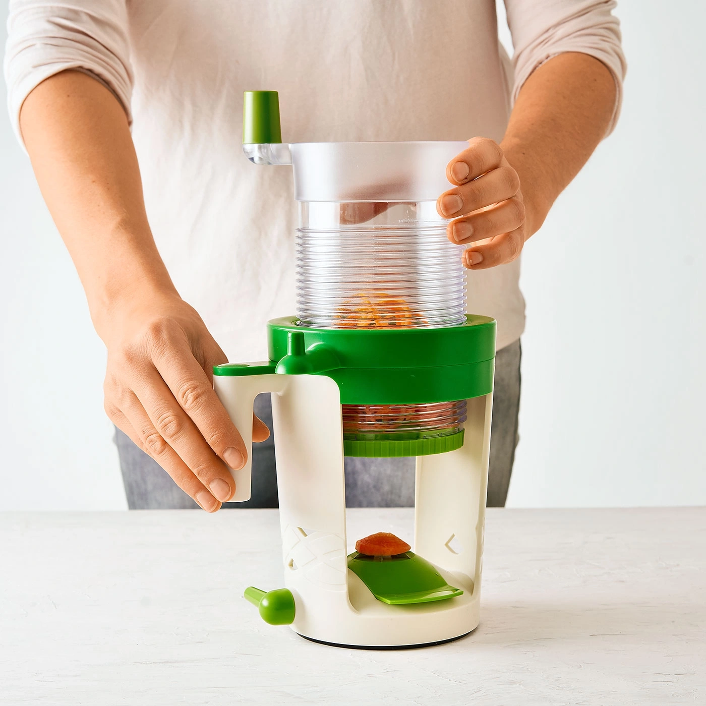 Une personne utilise un coupe-légumes. Les mains tiennent l'appareil. Les carottes sont coupées.