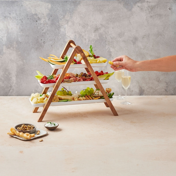 Plateau de fromages avec vin et collations, tenu par une main.