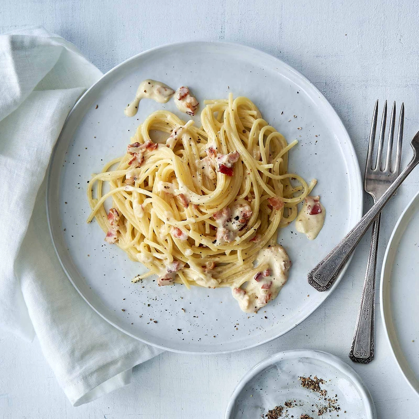 Spaghetti Carbonara auf einem Teller mit Gabeln und Serviette