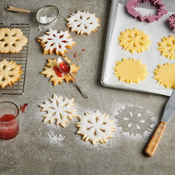 Biscuits en forme de flocons de neige avec sucre glace et confiture sur fond gris