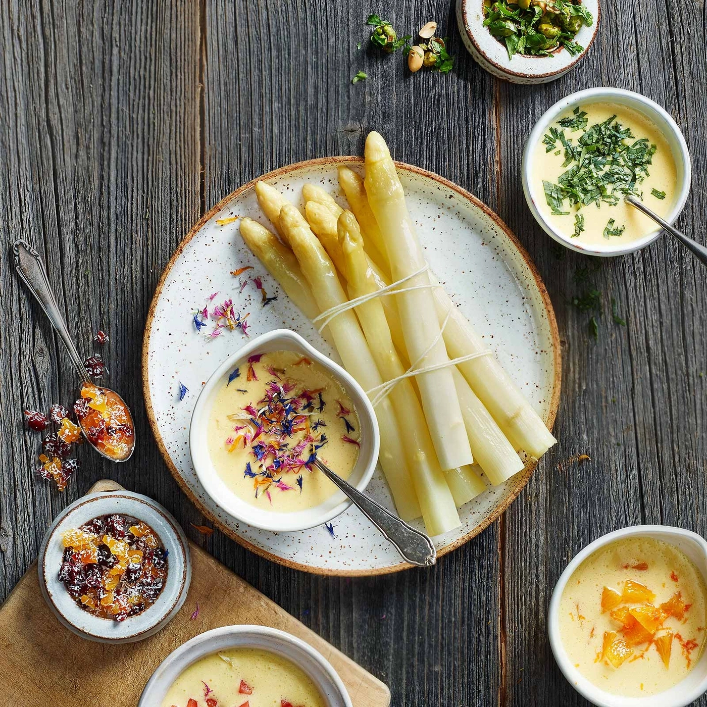 Spargel mit Sauce und Blüten auf Holzuntergrund, köstlich angerichtet.