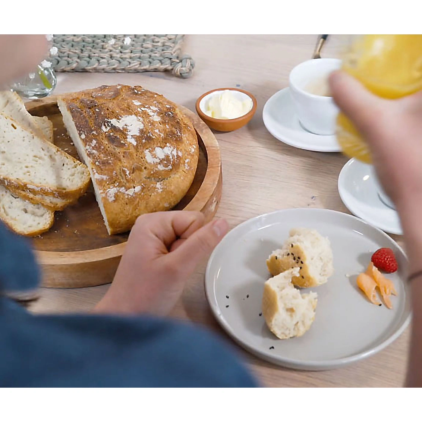 Frühstück mit Brot, Butter, Kaffee, Beeren und Orangensaft auf einem Holztisch.