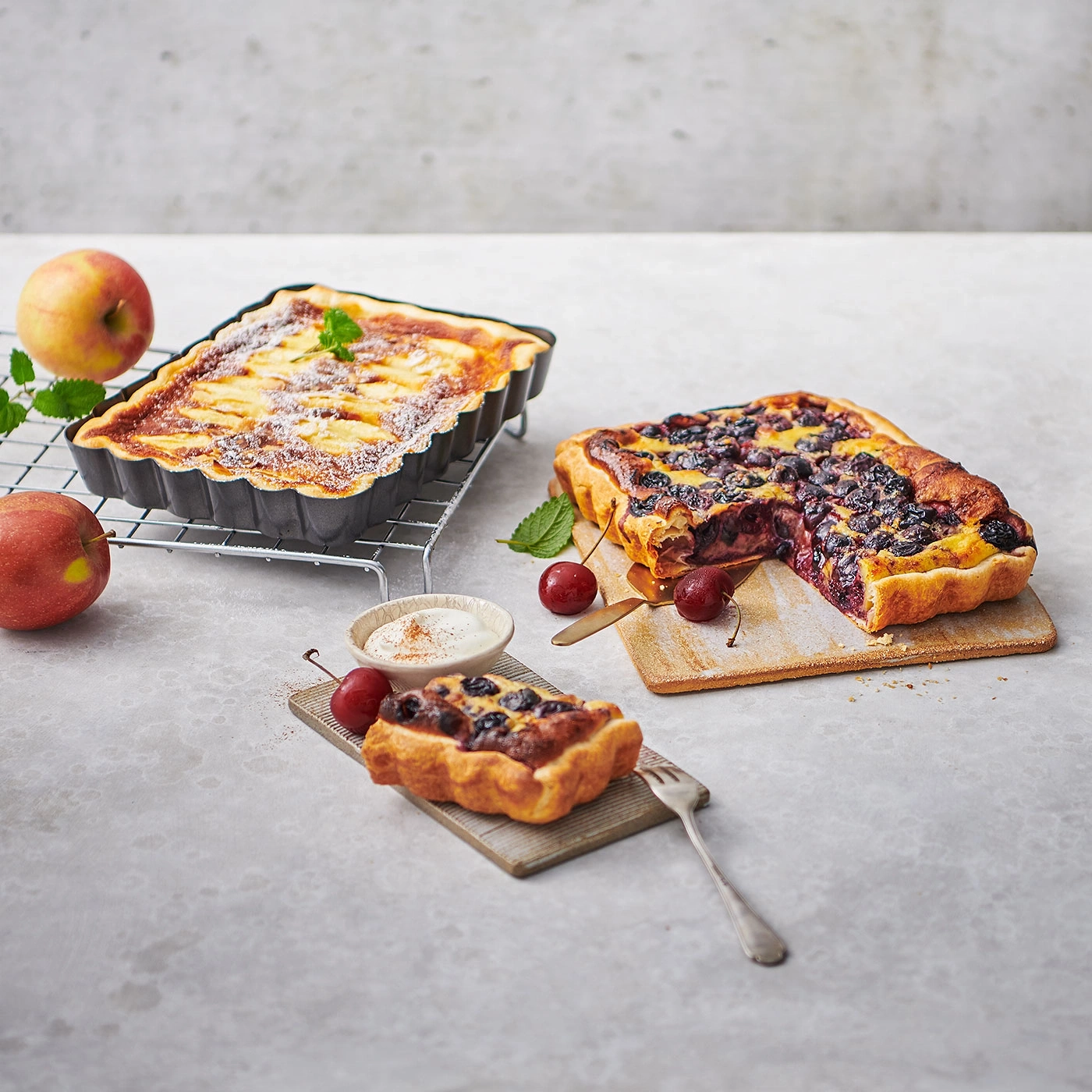 Kuchen mit Früchten, Kirschen, Äpfeln, Minze, auf Holzbrett und Gitter
