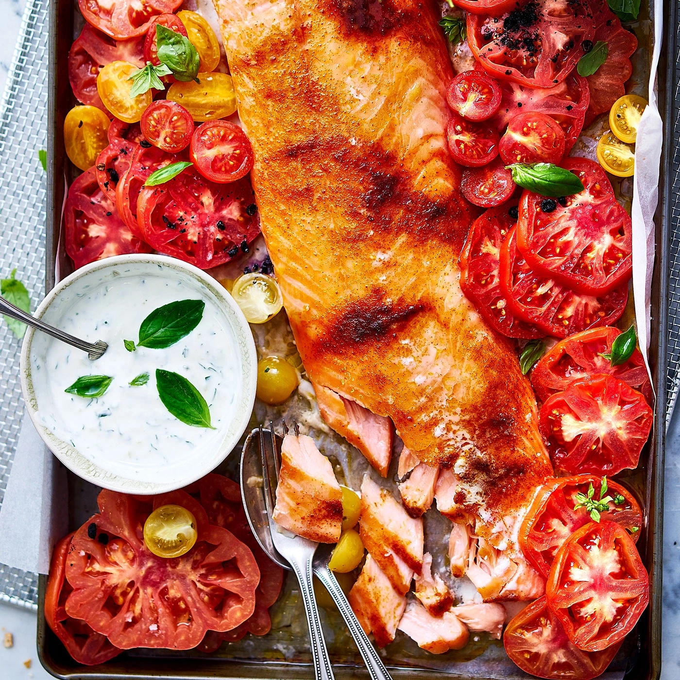 Saumon grillé avec tomates et sauce aux herbes sur une plaque de cuisson