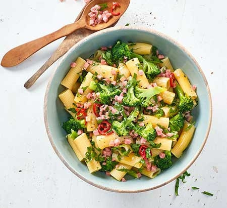 Pasta mit Brokkoli, Schinken und Kräutern in einer Schüssel mit Löffeln