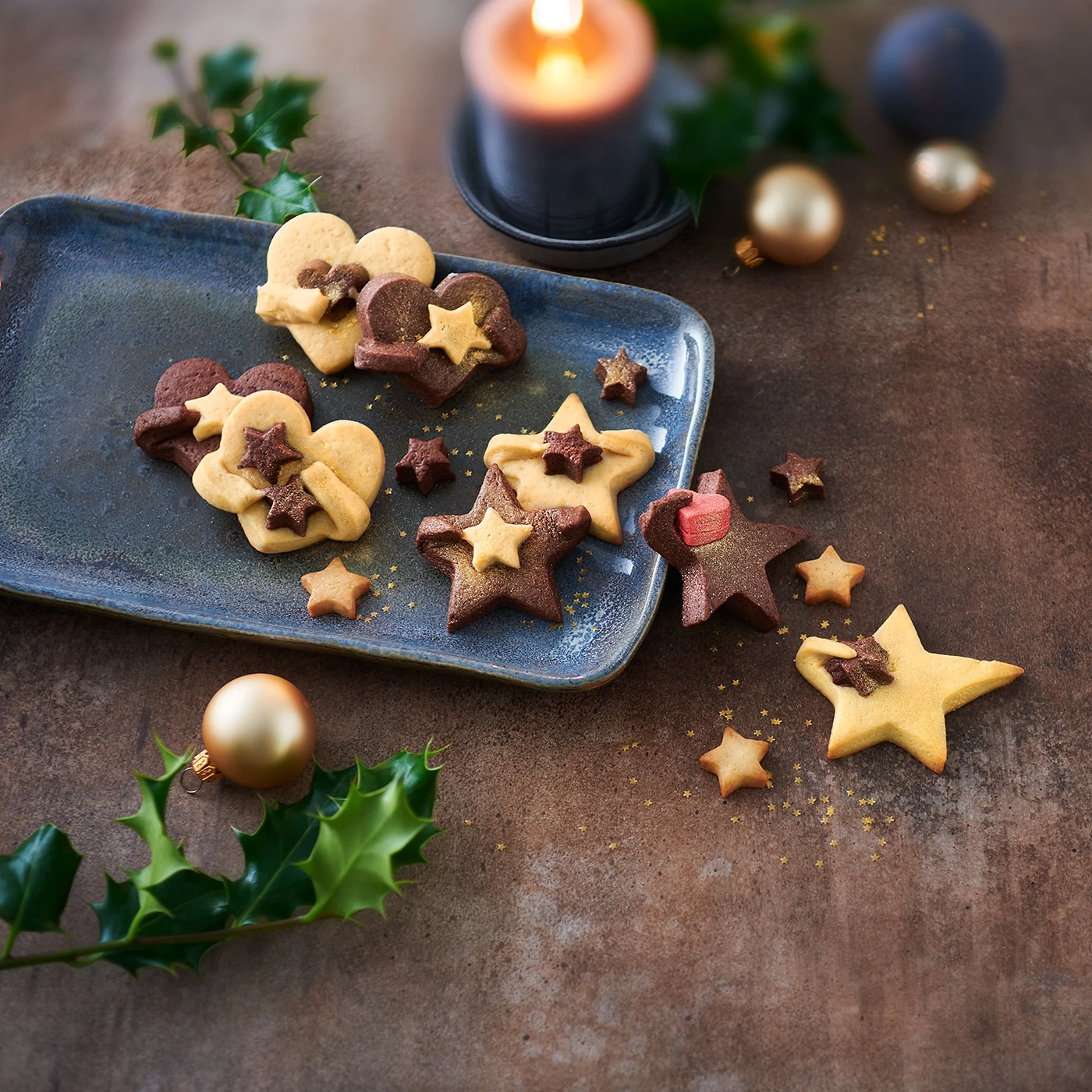 Biscuits de Noël sur une assiette avec décorations et bougie en arrière-plan.
