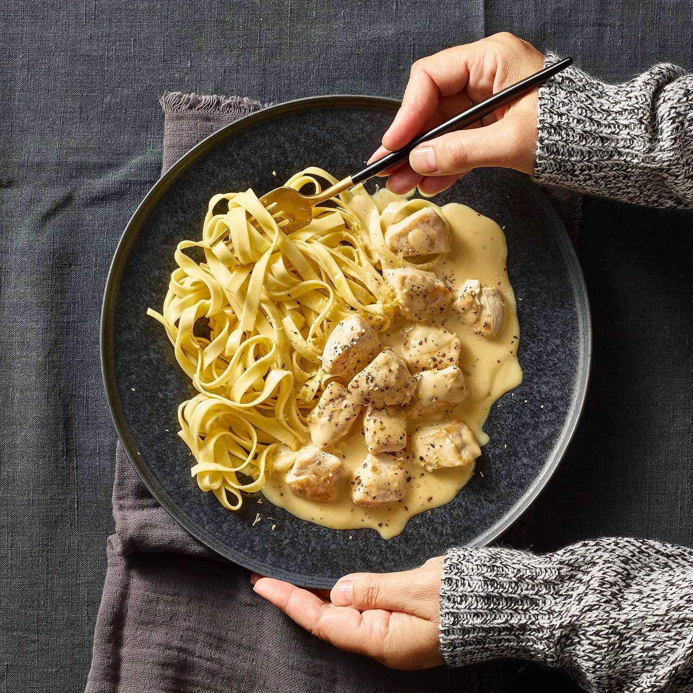 Teller mit Pasta und Hühnchen in cremiger Sauce, serviert mit einer Gabel.