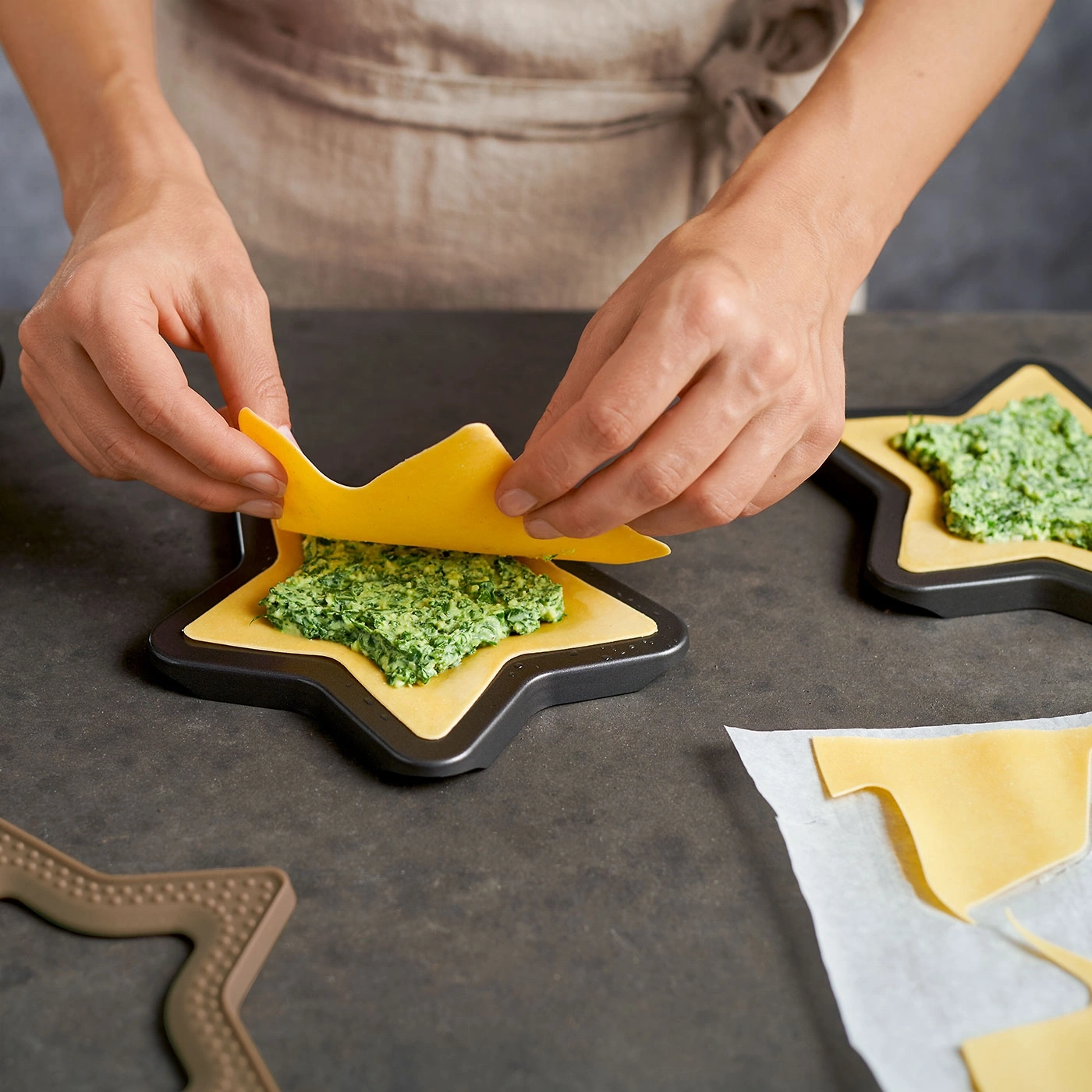 Personne fait des pâtes en forme d'étoile, garniture verte, pâte jaune, cuisine, nourriture