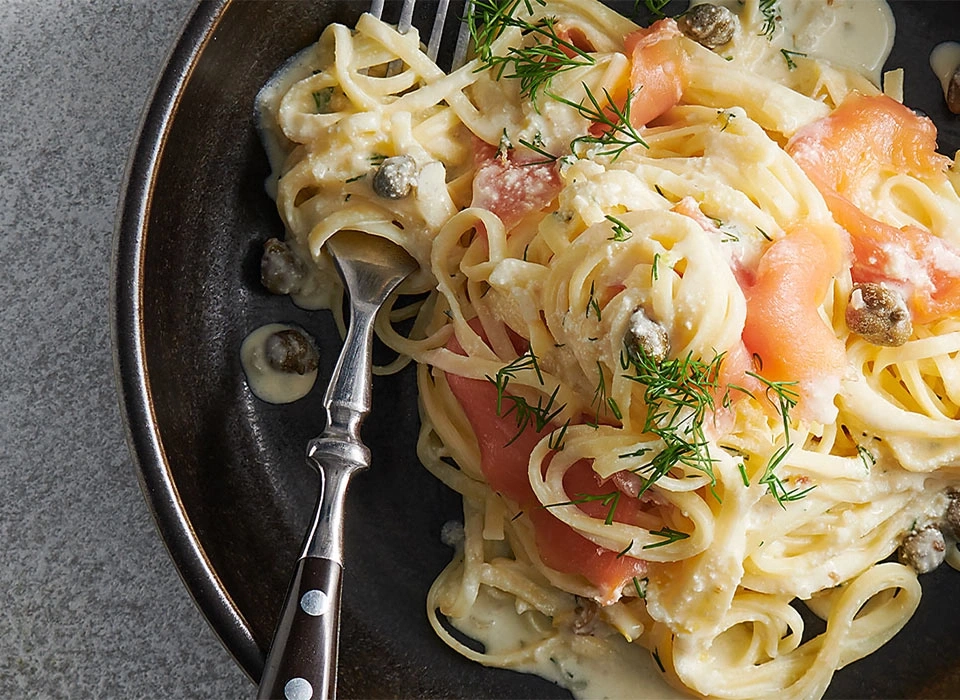 Pasta mit Lachs, Kapern und Dill auf einem Teller mit Gabel
