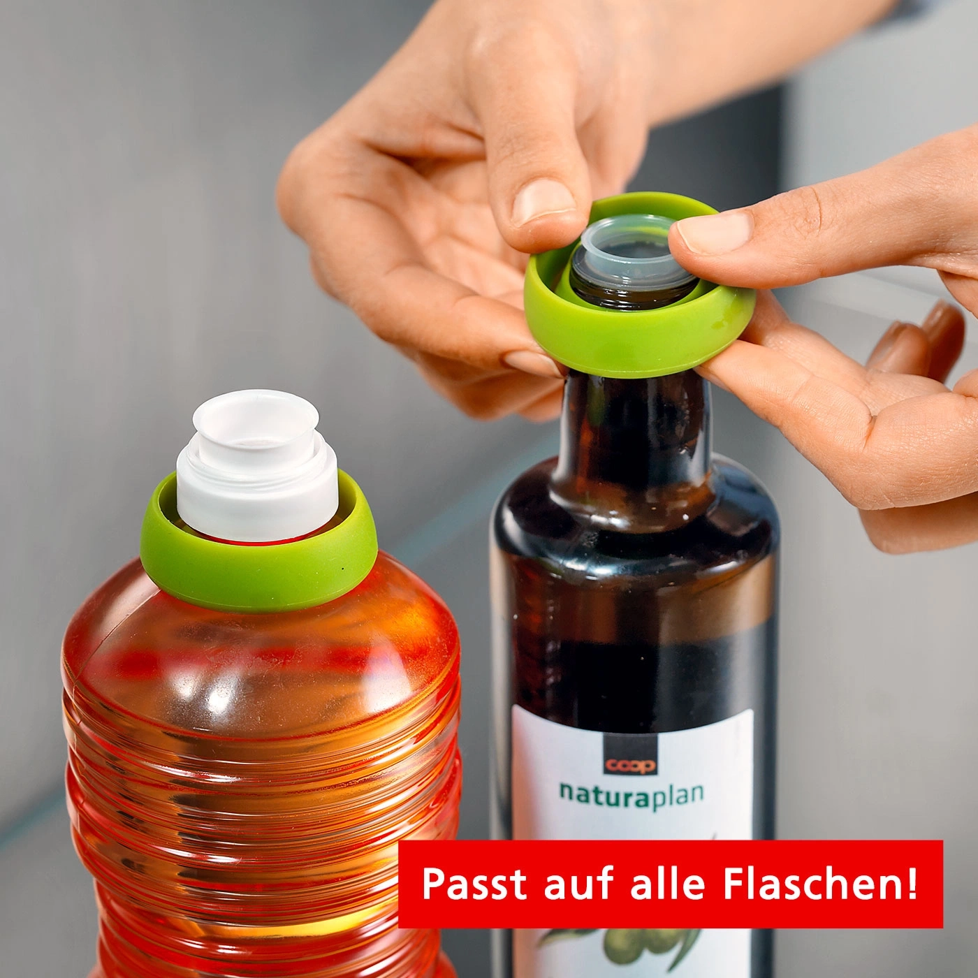 Hände halten grüne Flaschenverschlüsse auf Ölflaschen. Passt auf alle Flaschen!