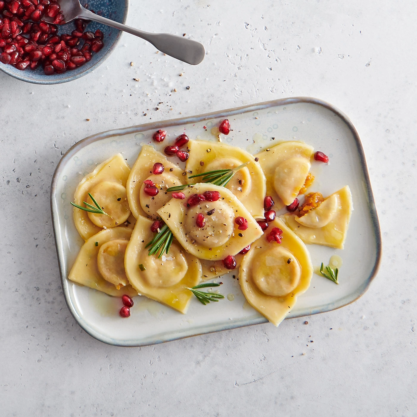 Raviolis avec graines de grenade et romarin, servis sur une assiette