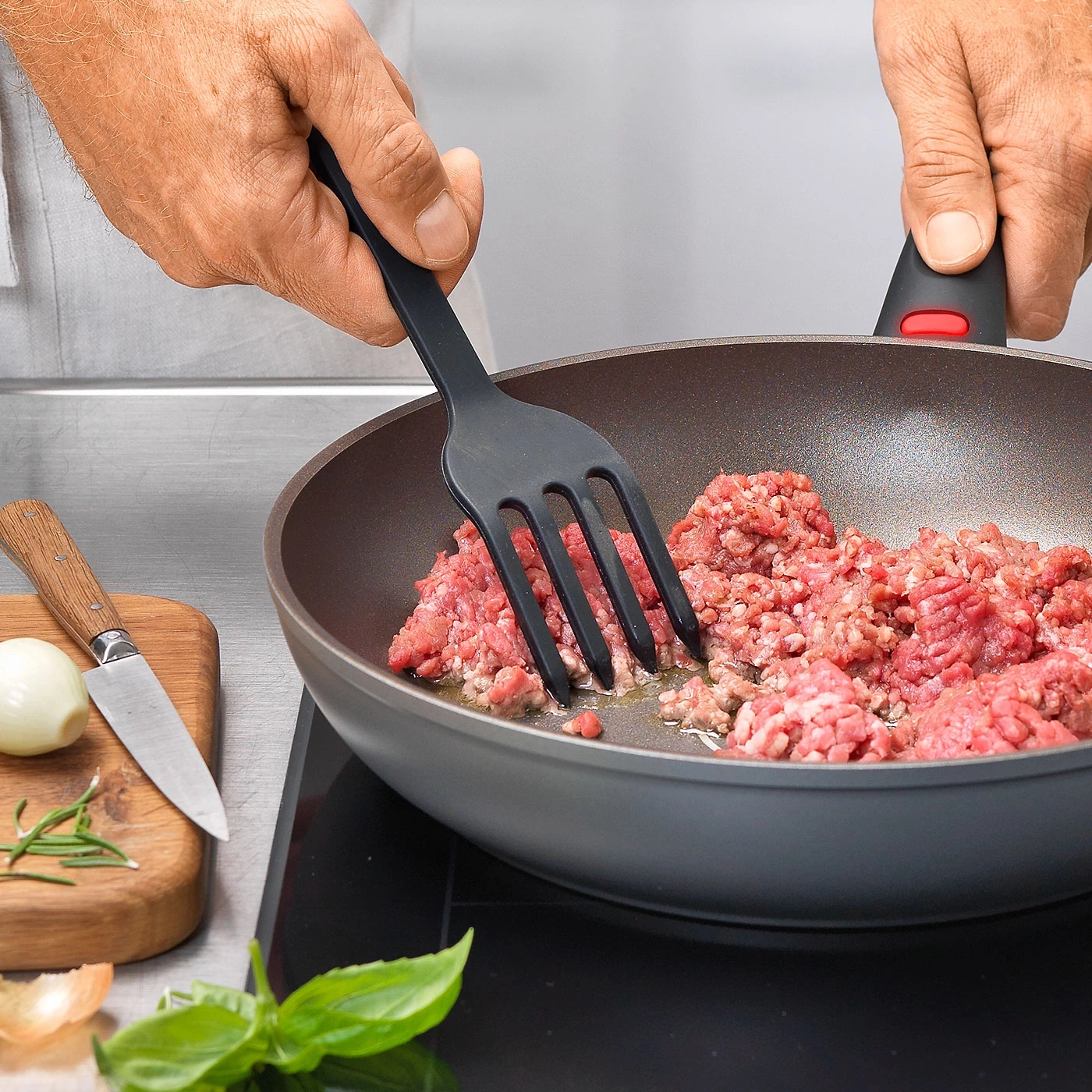 Person kocht Hackfleisch in einer Pfanne mit einem schwarzen Spatel.