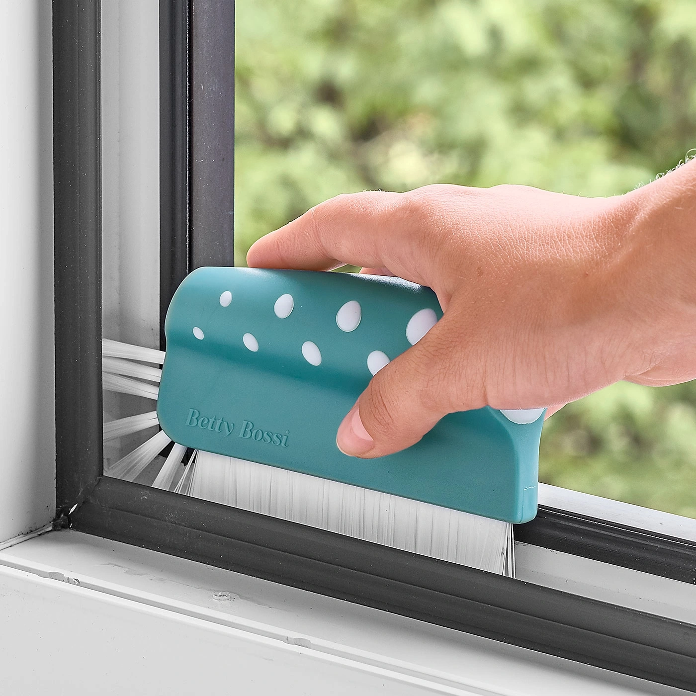 Gros plan d'une personne nettoyant le joint de fenêtre avec un outil de nettoyage spécial.