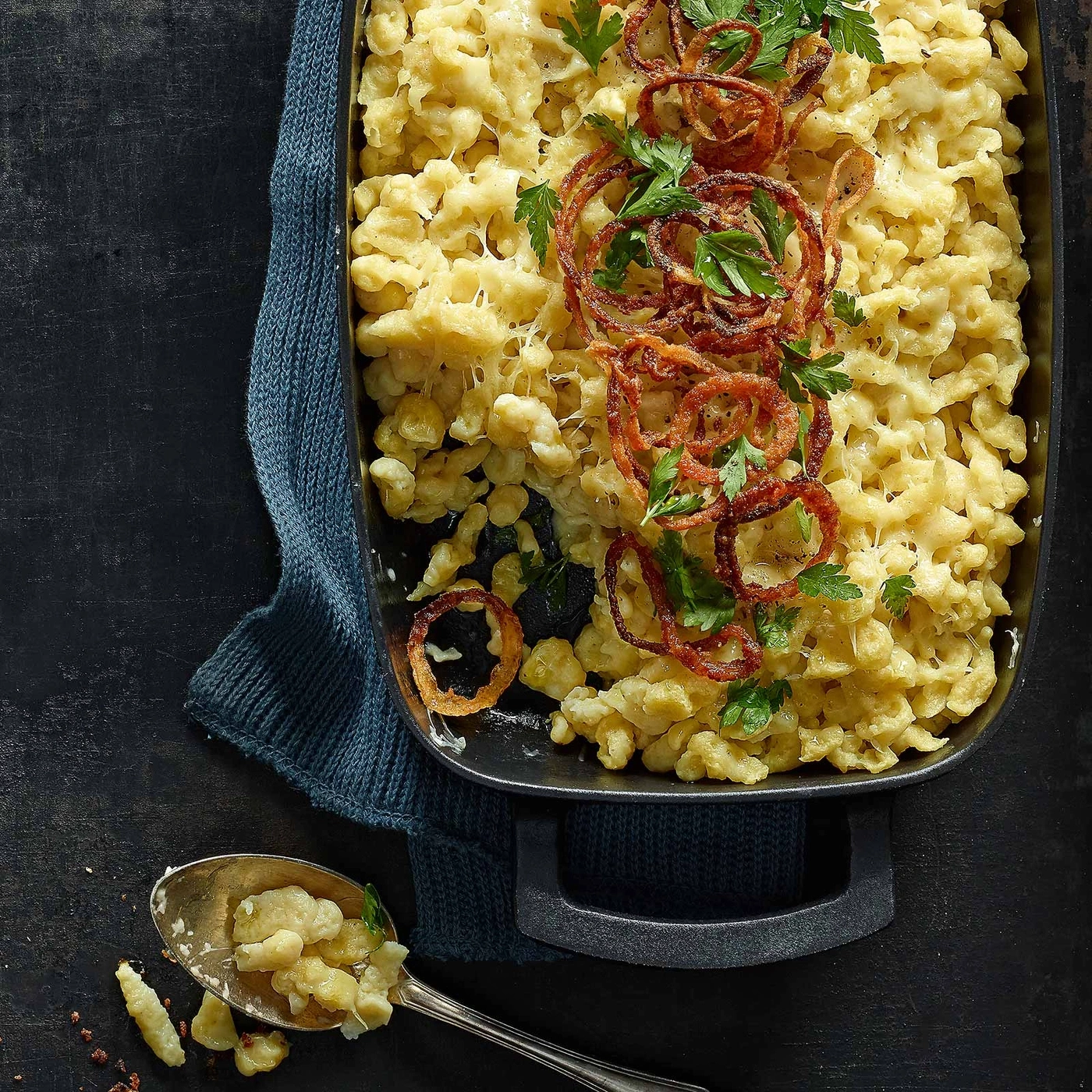 Käsespätzle mit Röstzwiebeln und Petersilie in einer schwarzen Auflaufform