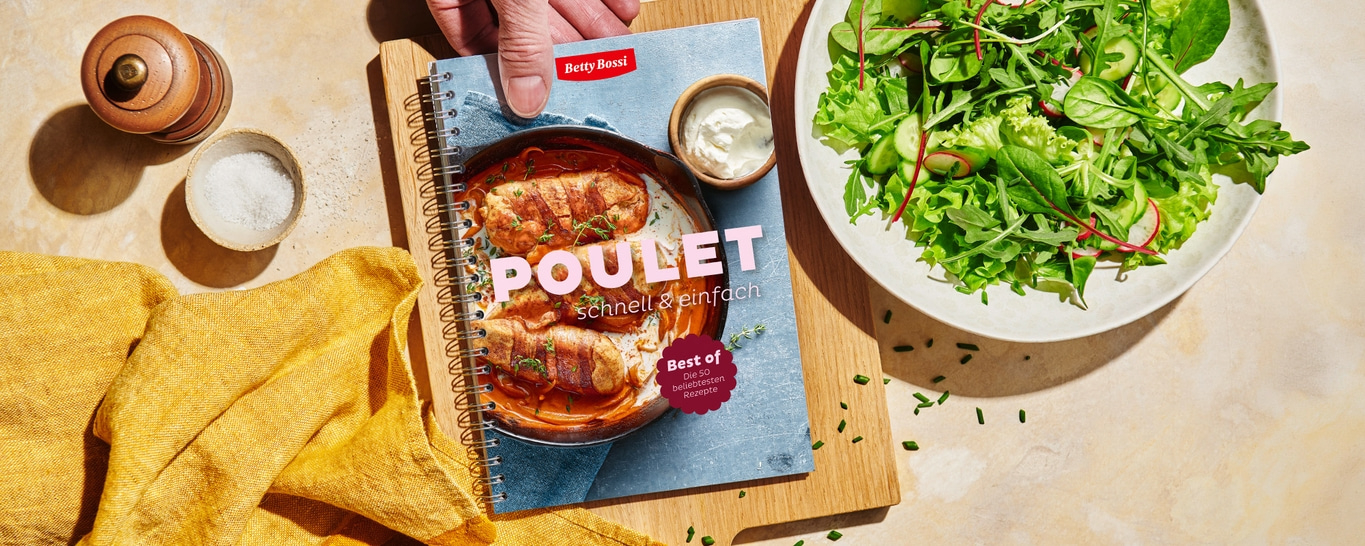Ein Kochbuch von Betty Bossi mit Poulet-Rezepten, daneben ein Salat.