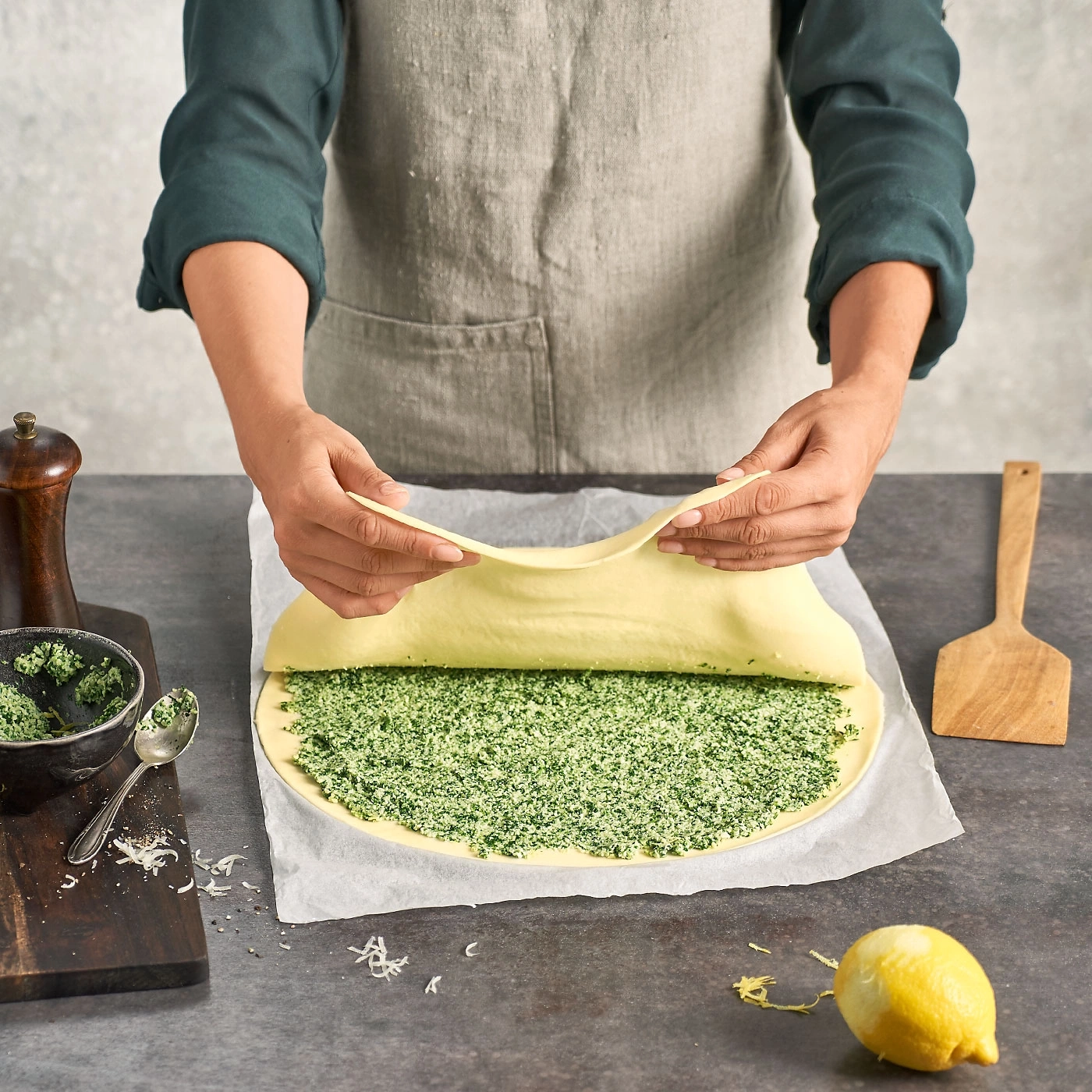 Personne roule la pâte sur une garniture verte, cuisine, cuisson, nourriture, recette