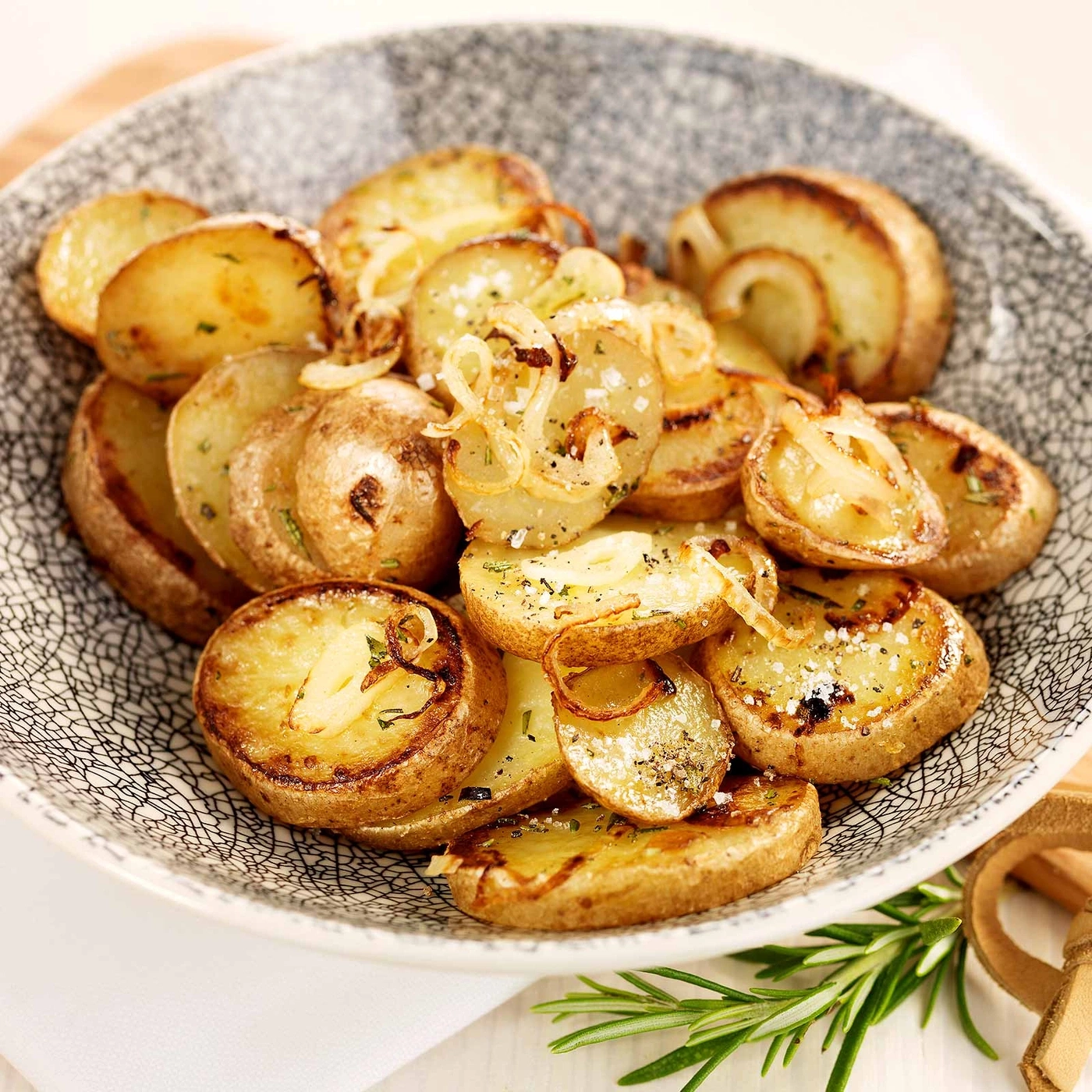 Gebratene Kartoffeln mit Zwiebeln und Kräutern in einer Schüssel, lecker.
