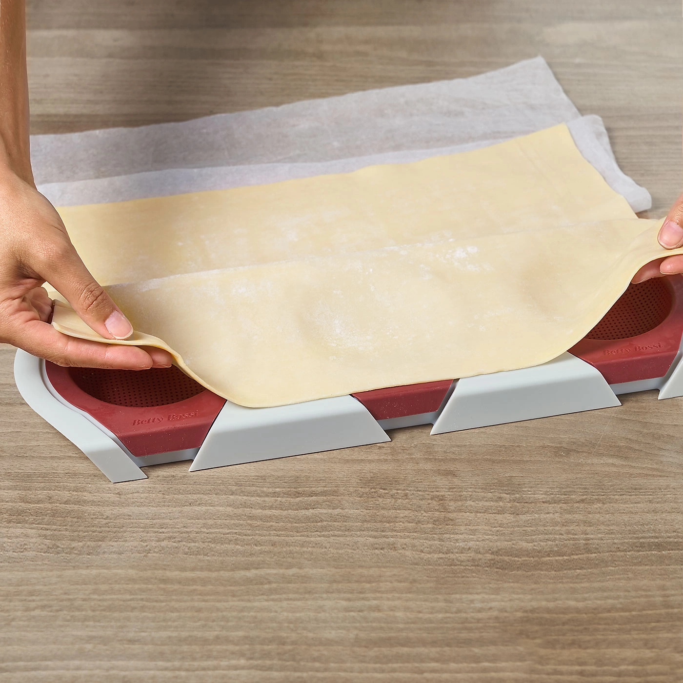 Mains tenant la pâte au-dessus d'un outil de cuisson sur une surface en bois. Cuisine, pâtisserie.